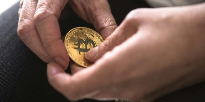 person holding round gold-colored Bitcoin